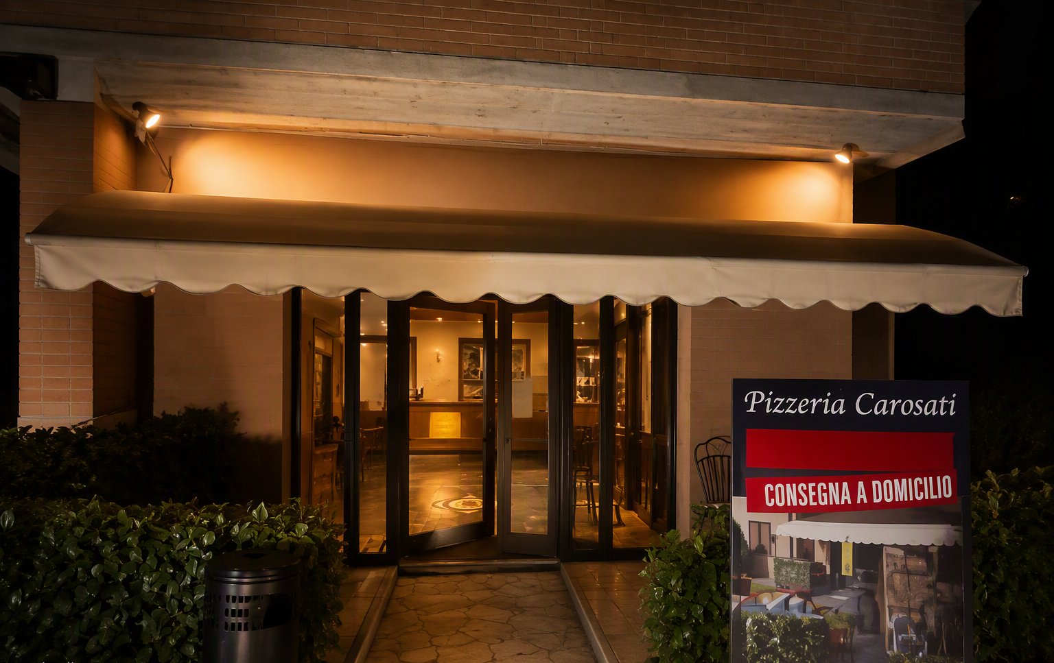 L'ingresso di sera con il cartello Consegna a domicilio